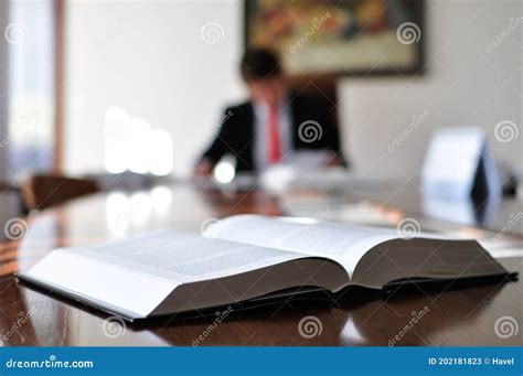 Close Up Of An Open Book On An Office Desk With A Blurred Man In The