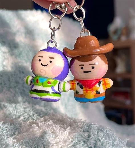 Two Toy Figures Are Holding Hands On A Keychain In The Shape Of A