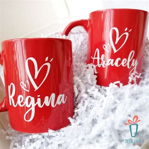 Two Red Coffee Mugs Sitting On Top Of White Shredded Paper With The