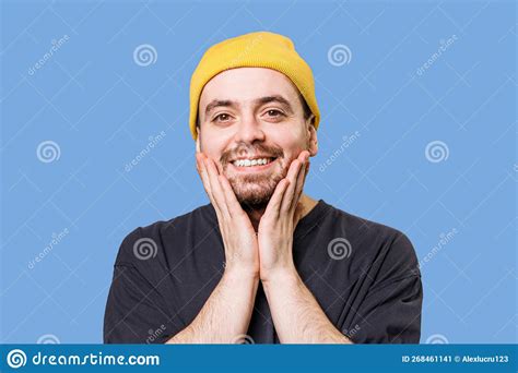 A Guy Wearing A Yellow Cap In A Studio Shot With A Cheerful Expression