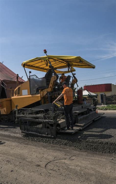 Worker Operating Asphalt Paver Machine During Road Construction And