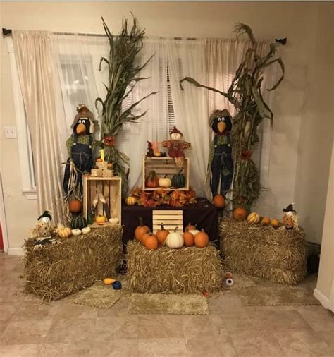 Hay Bales Filled With Pumpkins And Scarecrow Figurines On Top Of Them