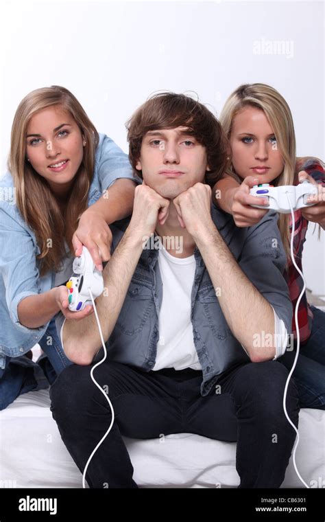 Bored teenager sat between two friends playing video games Stock Photo ...