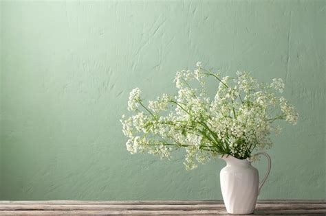 Flores Silvestres Blancas En Jarra En La Pared Verde De Fondo Foto