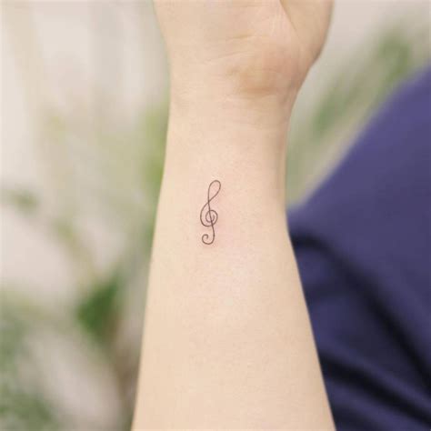 Minimalist treble clef tattoo on the wrist