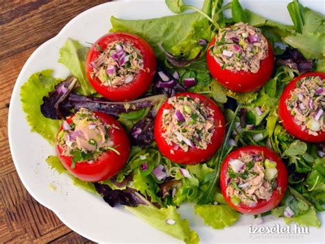 A White Plate Topped With Tomatoes And Lettuce On Top Of A Wooden Table