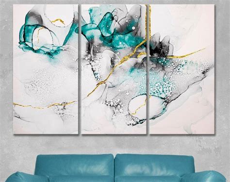 three abstract paintings on a wall in a living room with blue couch and ...