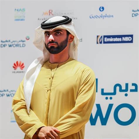 A Man In A Yellow Outfit Standing Next To A White And Blue Sign With