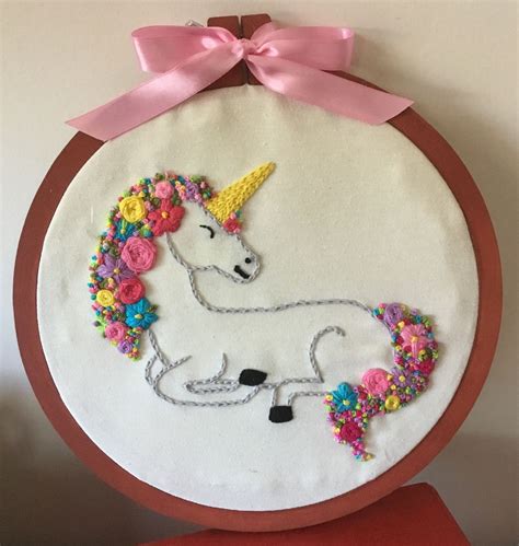 An Embroidered Unicorn With Flowers And A Pink Bow On It S Head Is Shown