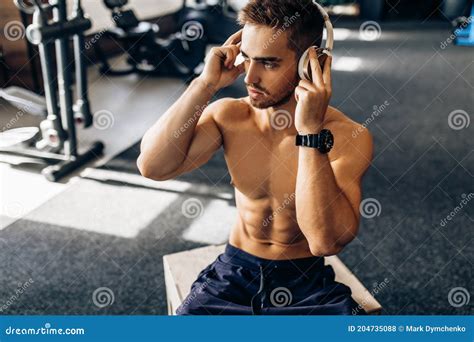 Muscular Young Fitness Man Shirtless Relaxing After Workout Listening To Music In Headphones