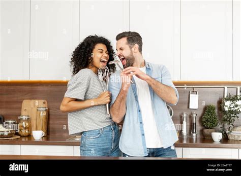 Happy Interracial Couple Dancing In The Kitchen Singing While Cooking