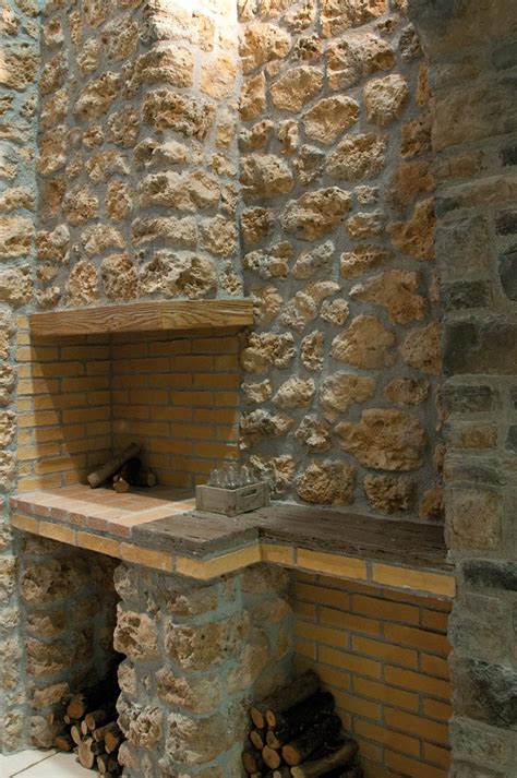 An Old Stone Fireplace With Wood Stacked On Top