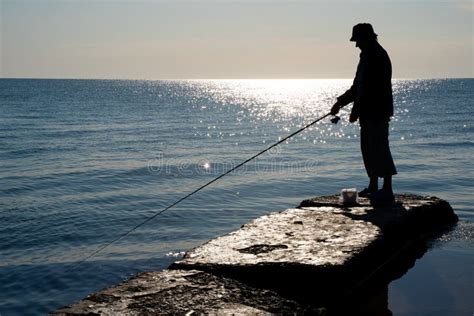 Silueta De Un Pescador Captura Pescado En El Mar Imagen De Archivo