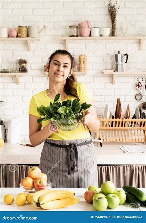 Young Brunette Smiling Woman Holding A Bowl Of Fresh Spinach In The