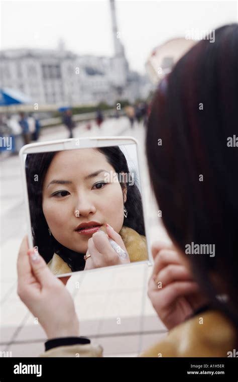 Close Up Of A Young Woman Looking Into A Mirror Applying Lipstick Stock