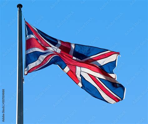 British Flag Union Jack Fluttering In The Breeze Against A Clear Blue