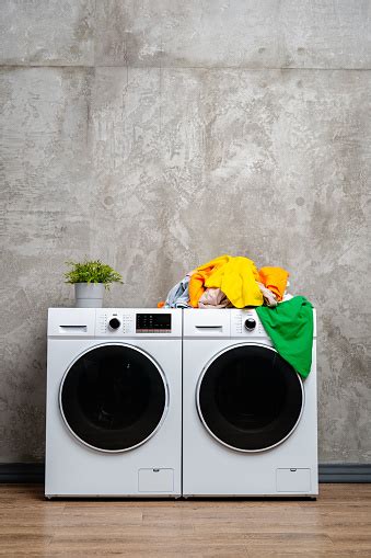 Modern White Washing Machines With Open Door And Laundry Basket In A