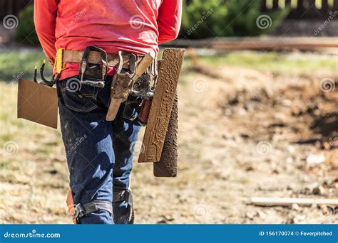 Cement Construction Worker With Toolbelt Holding Various Trowels And