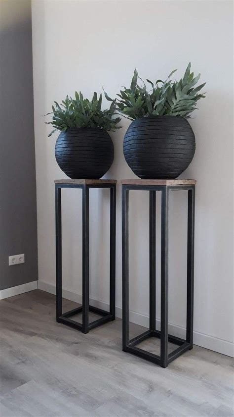 Two Black Vases Sitting On Top Of Each Other In Front Of A White Wall