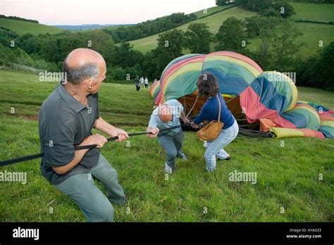 People Holding A Tether Rope As A Hot Air Baloon Deflates Stock Photo