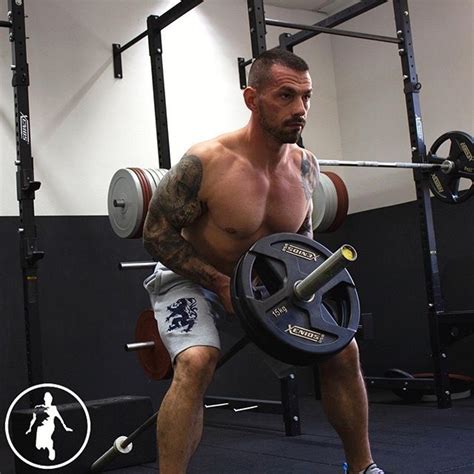 A Shirtless Man Lifting A Barbell In A Gym