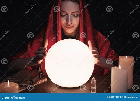 Soothsayer Using Glowing Crystal Ball To Predict Future At Table In