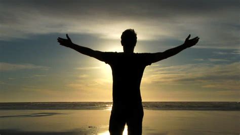 Model Released Person Standing With Arms Up In The Air On Sandy Beach