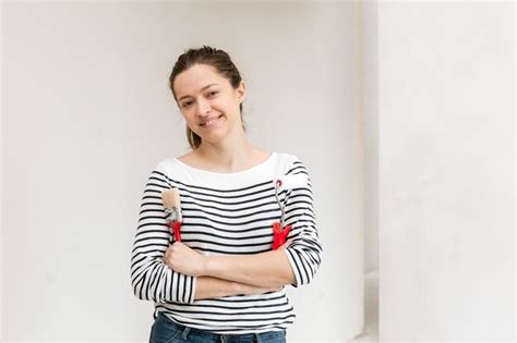 Premium Photo Young Woman Painting The Wall With Paint Roller And Brush