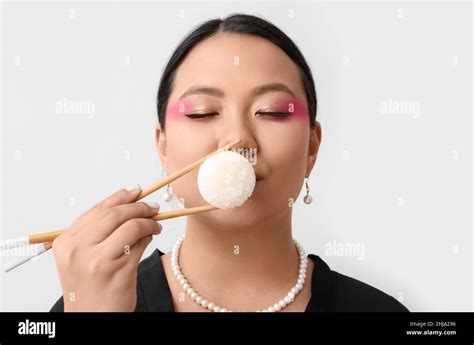 Beautiful Asian Woman Eating Tasty Japanese Mochi On Light Background