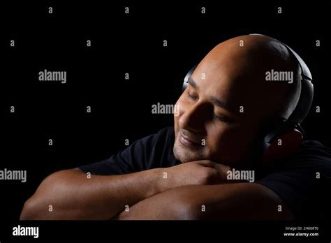 Portrait Of A Bald Man Listening To Music On Headphones With Closed