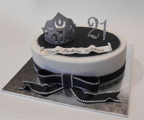 A White And Black Birthday Cake With Silver Decorations