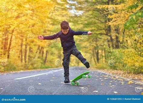 Kid Skateboarder Doing Skateboard Tricks In Autumn Environment Stock