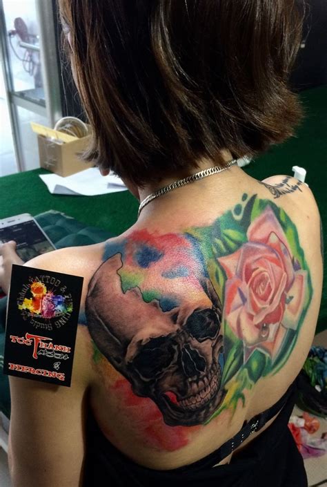 A Woman With A Skull And Rose Tattoo On Her Back