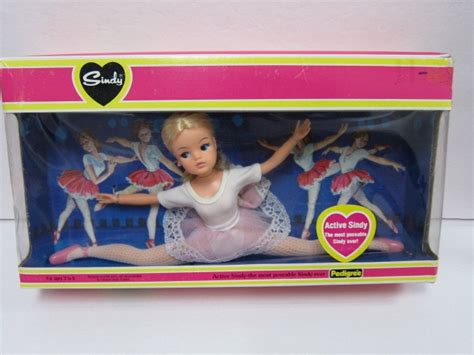 A Barbie Doll In A Pink And Yellow Box With Ballet Costumes On Its Back