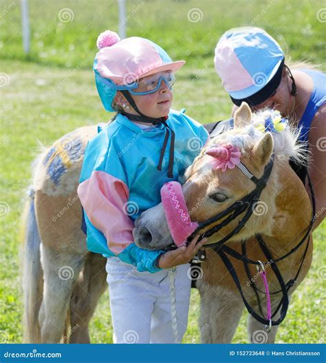 Young Jockey Holding A Cute Pony Dressed As A Unicorn On The Race Track