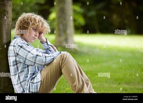 Sad Looking Boy Leaning Against Tree Stock Photo Alamy