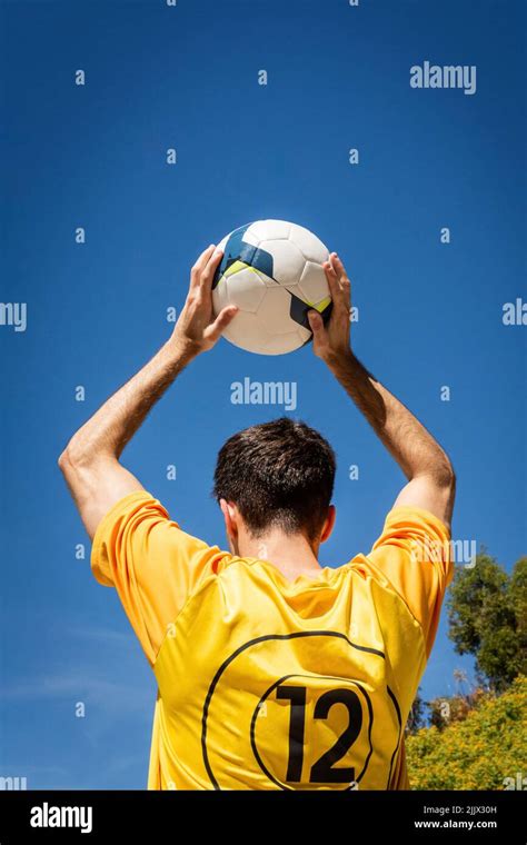 Back View Of Young Unrecognizable Male Soccer Player Holding Ball While