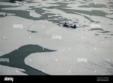 Fishermen Row Their Boats On Yamuna River Covered With Froth A Thick