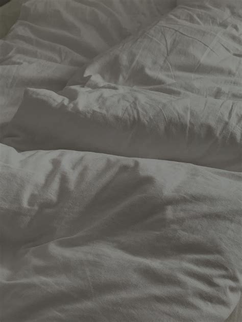 An Unmade Bed With White Sheets And Pillows