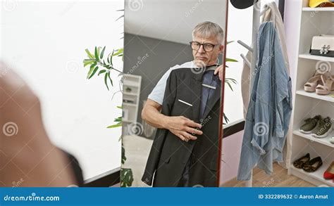 A Mature Man Tries On Suits In A Tidy Modern Dressing Room Reflecting
