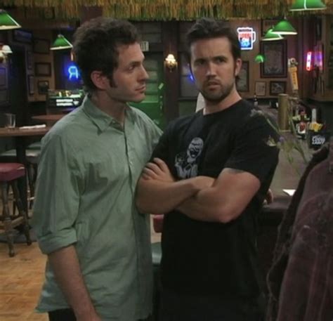 Two Men Standing Next To Each Other In A Room With Tables And Bar Stools