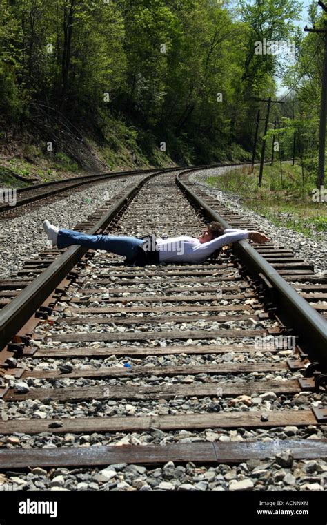 Woman Lying On Railroad Tracks With Hands And Feet Bound Stock Photo