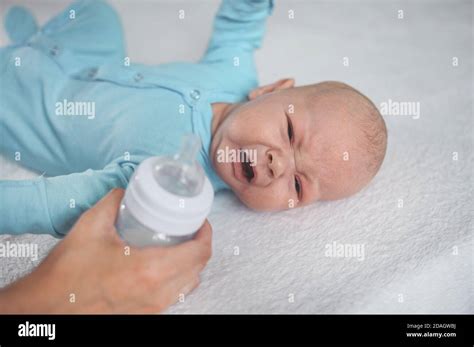 Cute Emotional Crying Newborn Boy Laying On Bed With Milk Bottle Baby