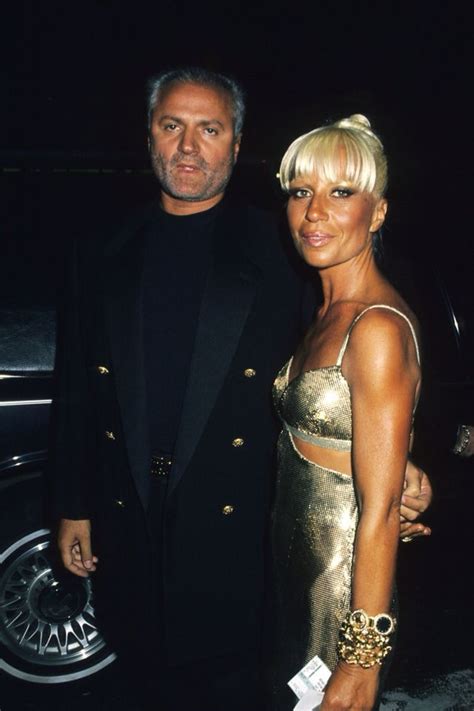 A Man And Woman Standing Next To Each Other In Front Of A Car At An Event