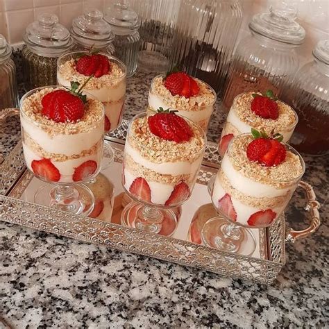 Four Desserts With Strawberries On Top Sit On A Silver Tray In The Kitchen