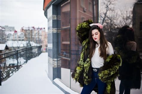 Premium Photo Brunette Girl In Green Fur Coat At Street Of City Against House With Large