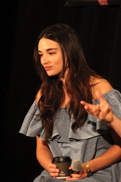 A Woman In A Blue Dress Is Holding A Microphone And Talking To Someone