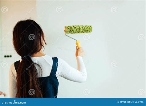 Happy Woman With Roller Brush Standing Against Wall Stock Image