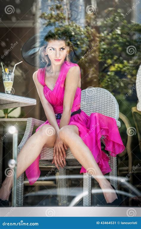 Fashionable Attractive Young Woman In Pink Dress Sitting In Restaurant Beyond The Window