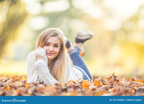 Autumn Portrait Of Young Woman Lying On Maple Leaves In Park Stock